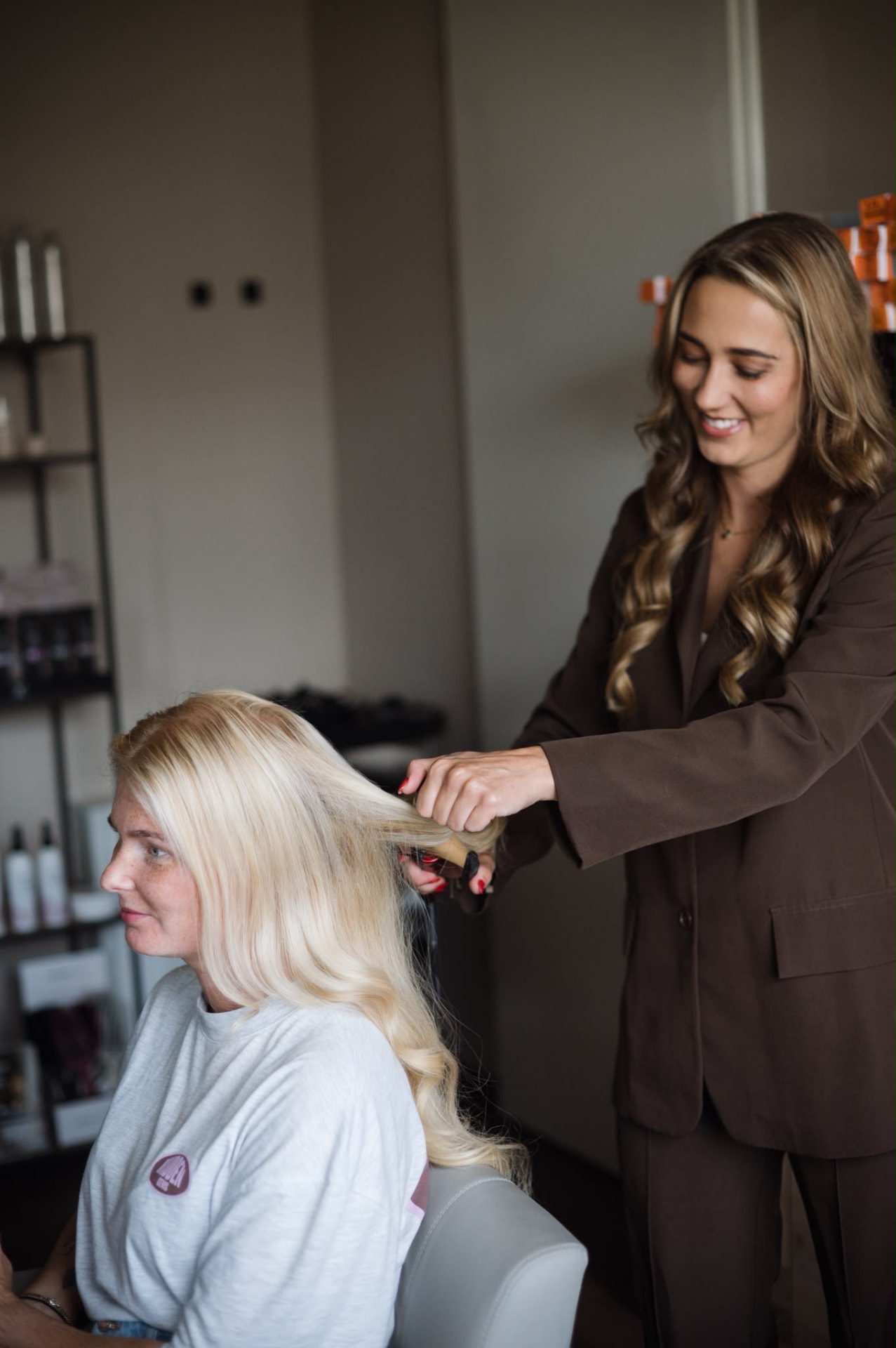 Quirine föhnt het blonde haar van een klant in de salon